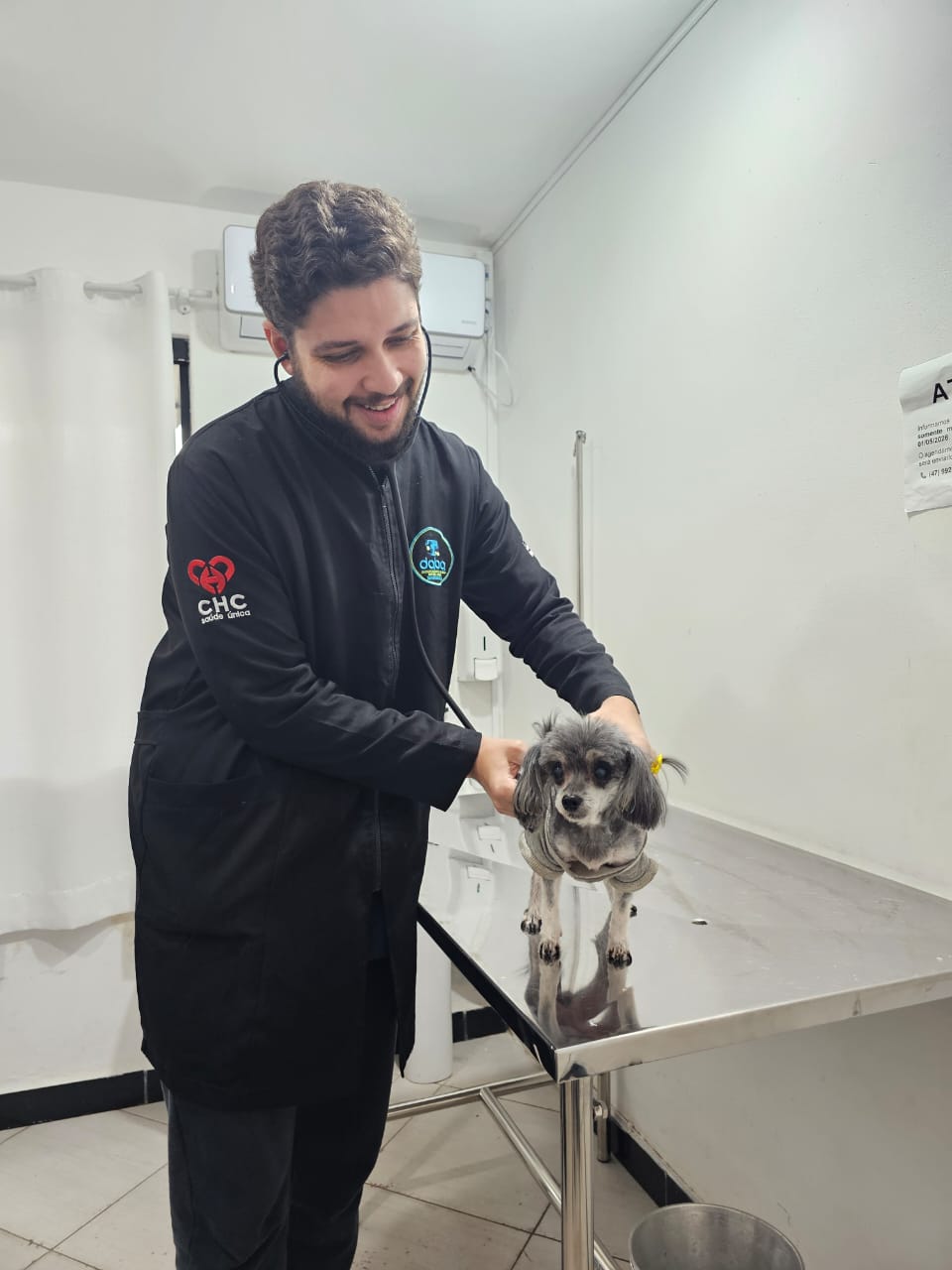 Veterinário com uniforme CHC Saúde Única realizando consulta em cão